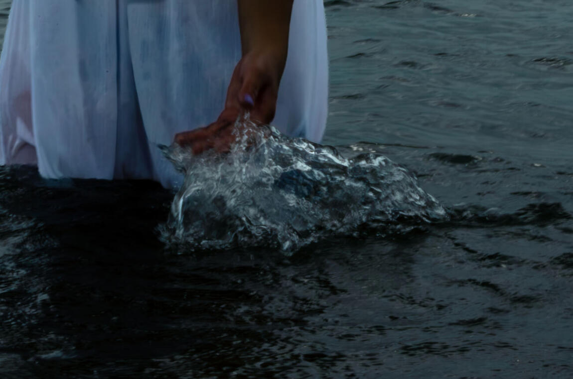 A hand lifting a sheet of lake water mid-splash